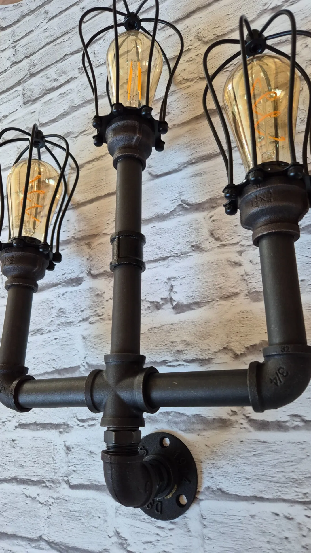 Kézzel épített ipari lámpa közelről, fekete vízcső részletekkel és világító Edison izzóval — Dizájnvill kézműves munka
